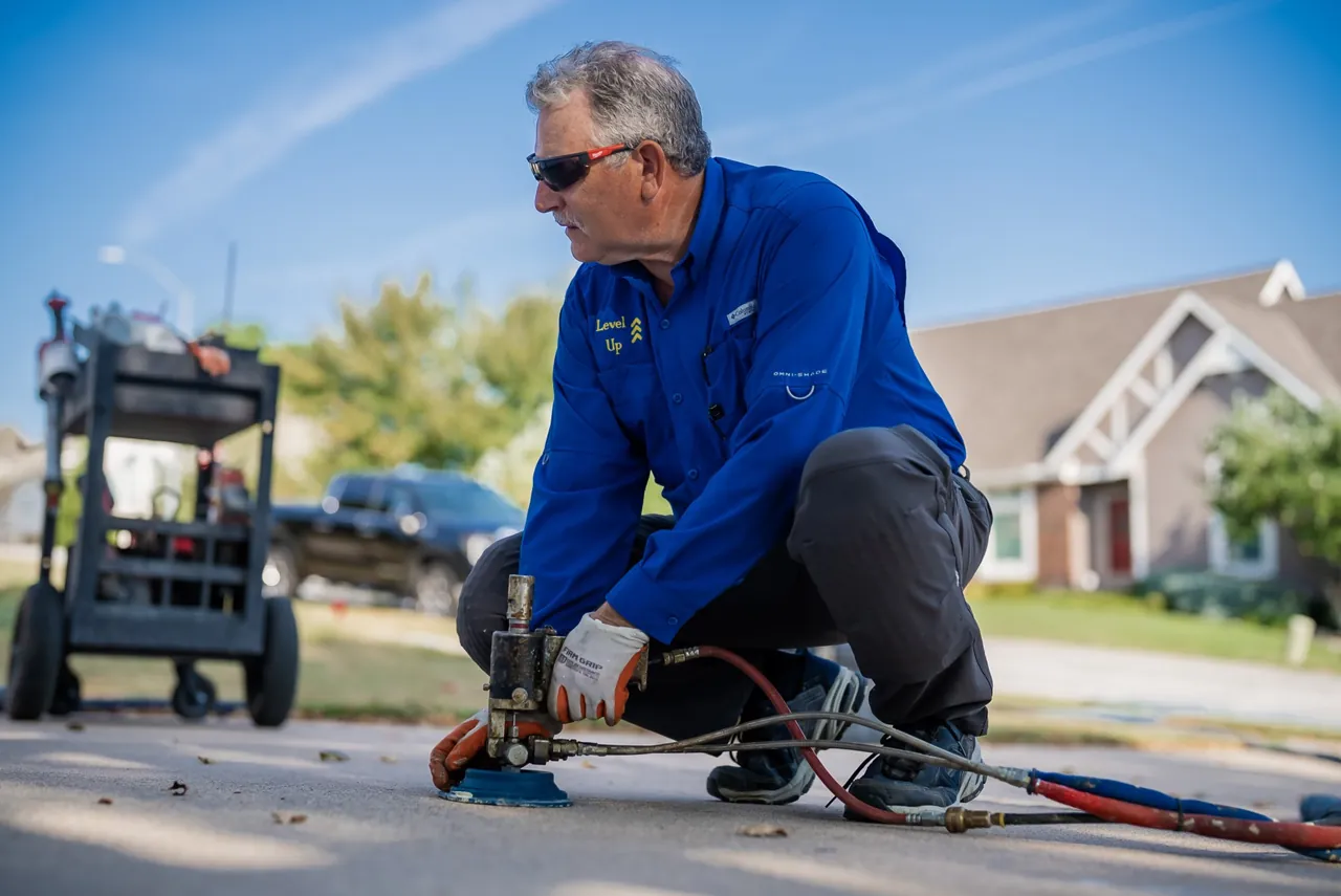 Level Up technician operating polyurethane lifting equipment on a residential driveway