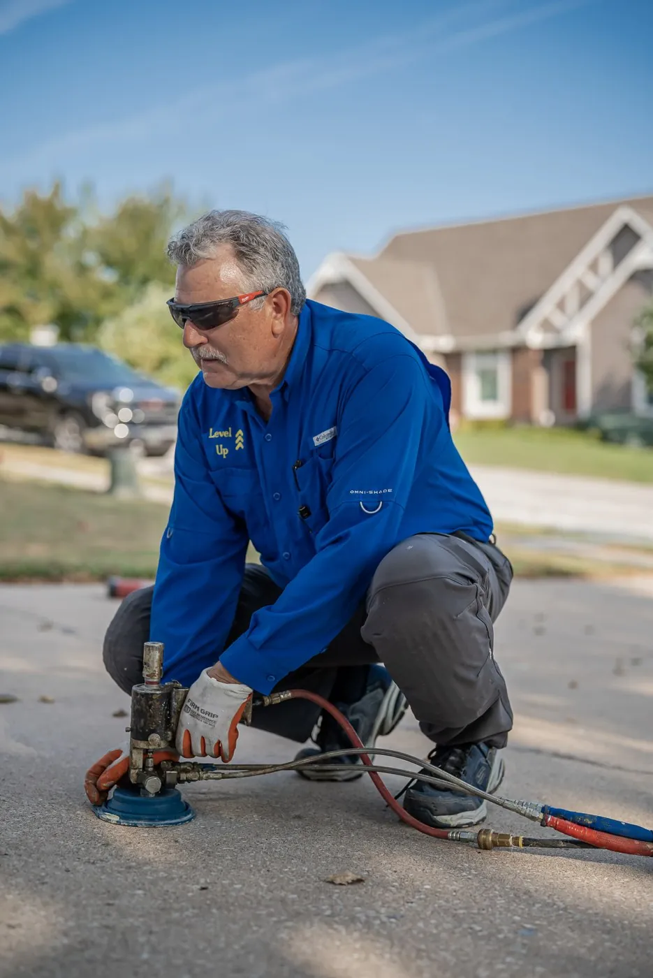 Technician injecting polyurethane beneath a driveway